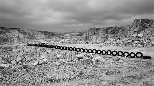 A stark quarry landscape crossed by a line of tires