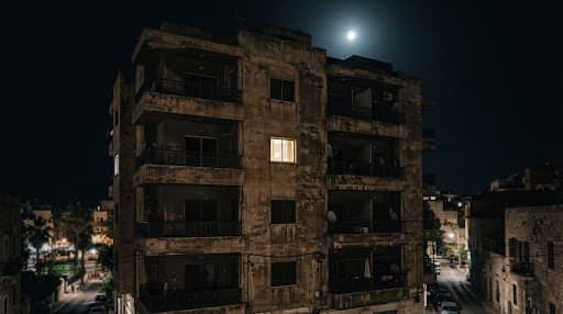 A weathered apartment facade beneath moonlight