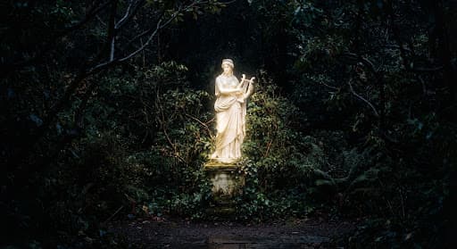 A luminous statue amid a dark, overgrown garden